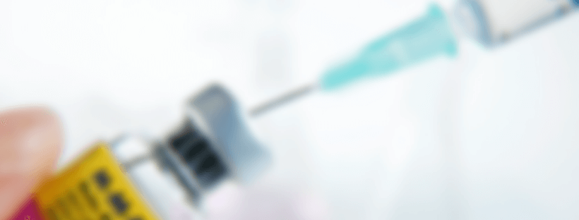 blurred vial of vaccine and syringe going into it