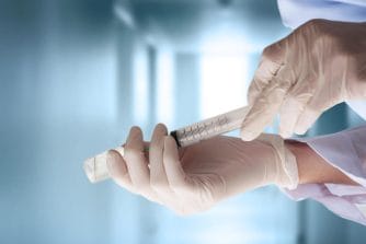 Medical professional hands wearing gloves holding vaccine
